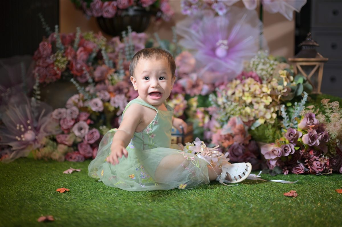 Tanya smiling in a sage green dress, seated among flowers