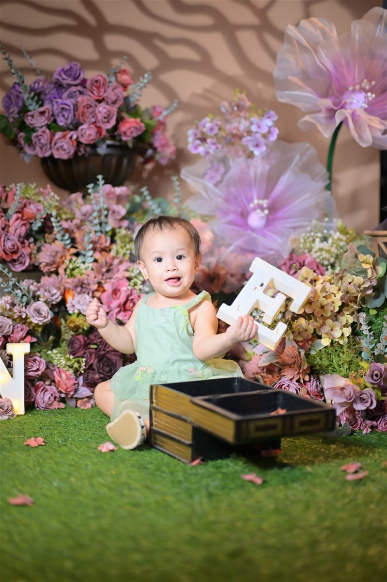 Tanya smiling and holding a letter E beside a gold and black box
