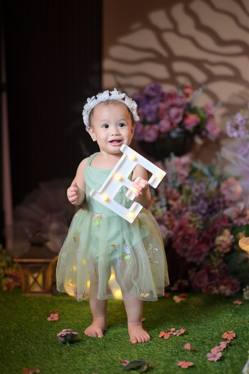 Tanya wearing a white floral headband and holding a light-up letter E
